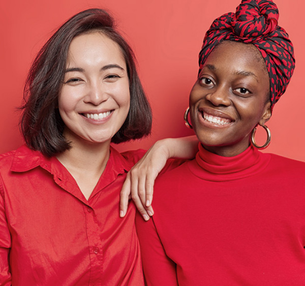 Two smiling women on red background, symbol of inclusion, diversity and social responsibility, key values of Yex Change