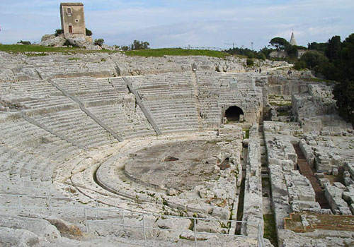 View of the Greek Theatre of Syracuse, an ancient amphitheatre carved into the rock surrounded by Mediterranean vegetation